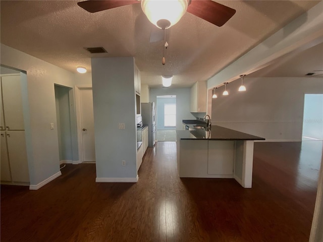 kitchen featuring ceiling fan, kitchen peninsula, a textured ceiling, white cabinetry, and dark hardwood / wood-style floors