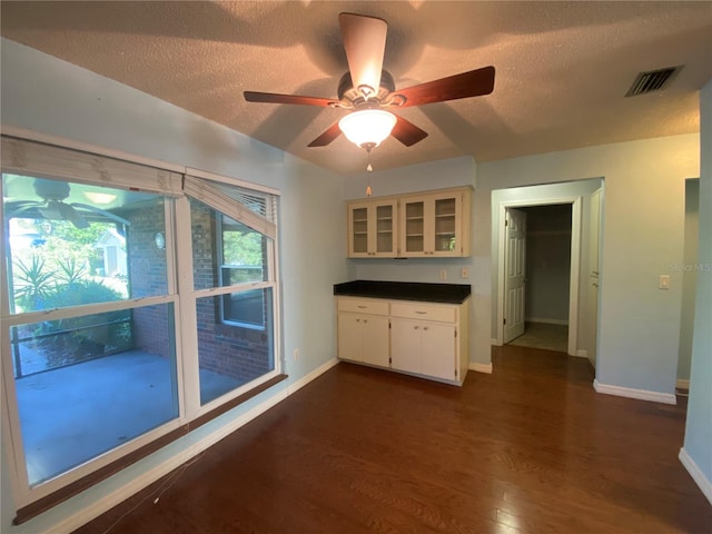 kitchen with a textured ceiling, white cabinetry, dark wood-type flooring, and ceiling fan