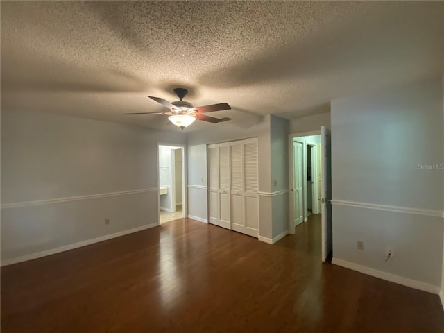 unfurnished bedroom with a textured ceiling, connected bathroom, dark hardwood / wood-style floors, and ceiling fan