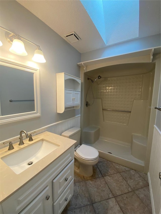 bathroom with a textured ceiling, a shower, vanity, and toilet