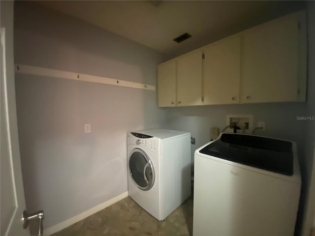 laundry room with separate washer and dryer and cabinets