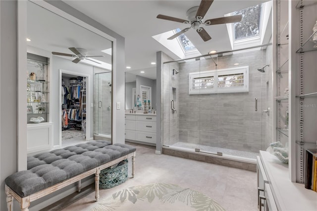 bathroom featuring lofted ceiling with skylight, vanity, ceiling fan, and a shower with shower door