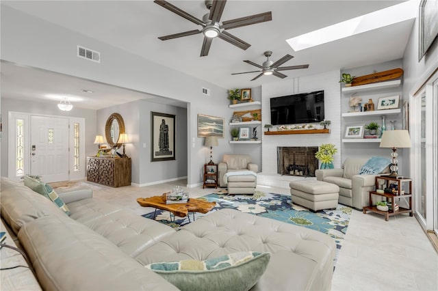 tiled living room with ceiling fan, a skylight, and a fireplace