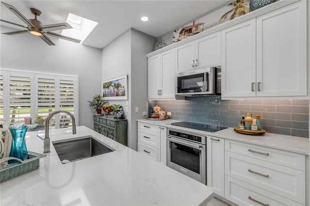 kitchen with light stone counters, white cabinets, ceiling fan, sink, and appliances with stainless steel finishes