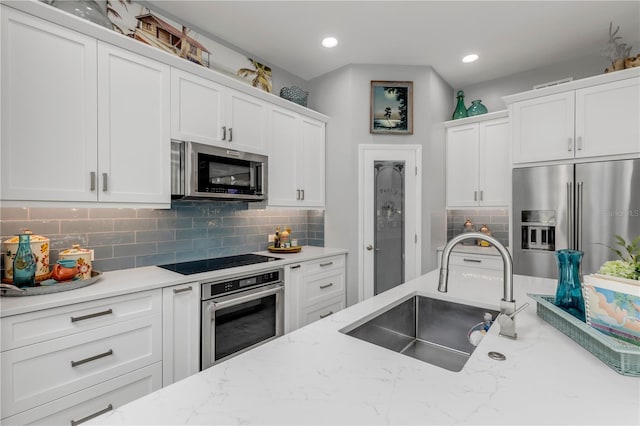 kitchen with light stone countertops, white cabinetry, appliances with stainless steel finishes, and sink