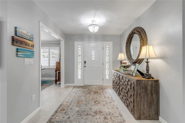 tiled entryway featuring an inviting chandelier