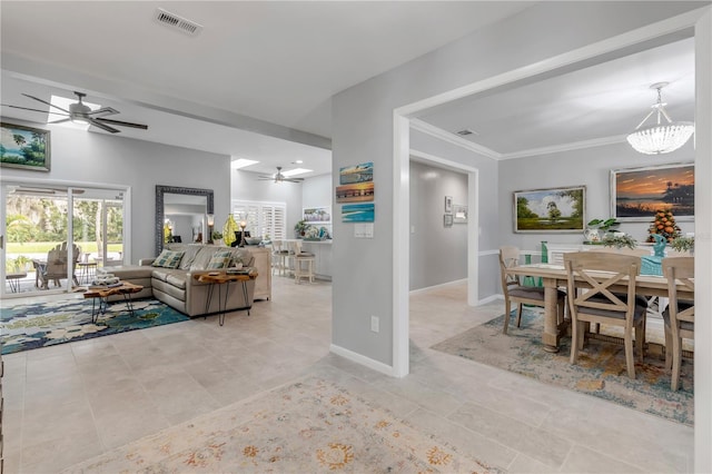 tiled living room with ceiling fan with notable chandelier and crown molding