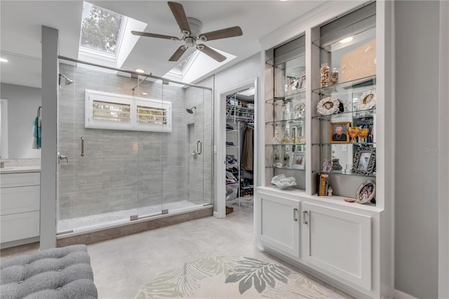 bathroom with ceiling fan, vanity, vaulted ceiling with skylight, and an enclosed shower