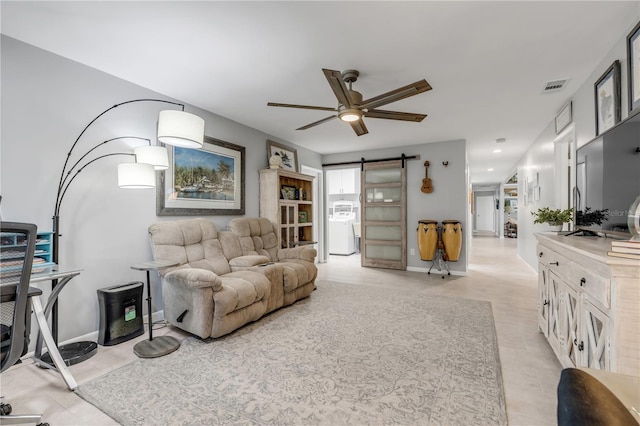 living room with ceiling fan, washer / clothes dryer, and a barn door