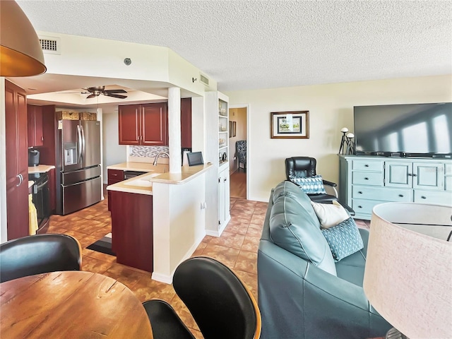 kitchen featuring a textured ceiling, stainless steel fridge, sink, and ceiling fan