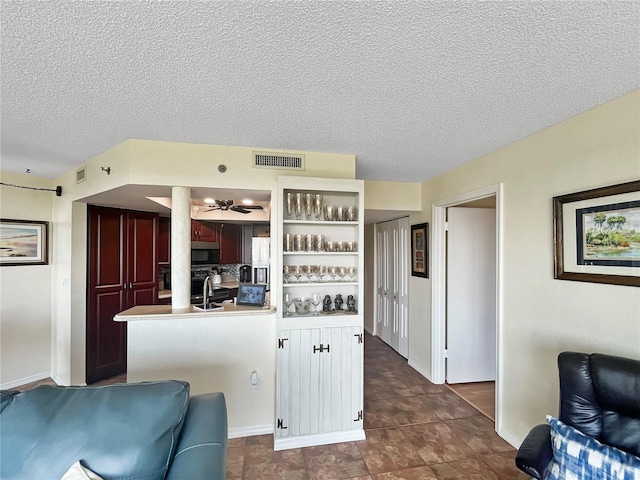 kitchen featuring dark tile patterned flooring, kitchen peninsula, a textured ceiling, and sink