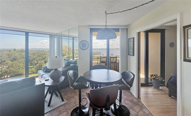 dining space featuring a textured ceiling, a wall of windows, light hardwood / wood-style flooring, and a wealth of natural light