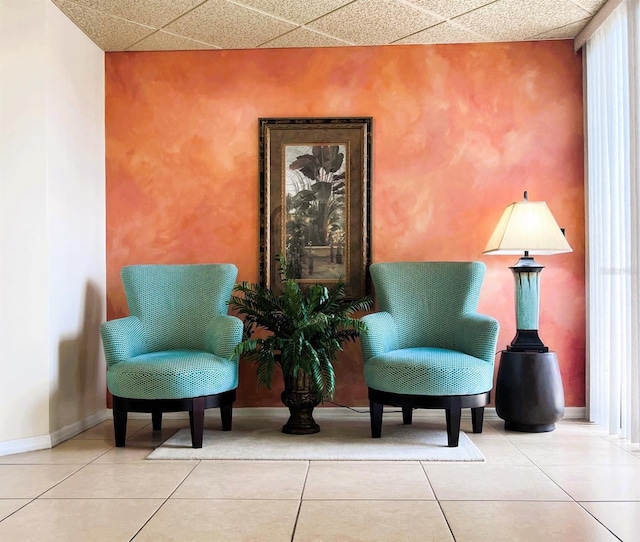 living area featuring tile patterned floors and a paneled ceiling