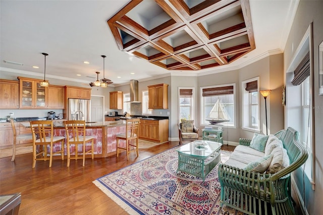 living room featuring beam ceiling, coffered ceiling, light hardwood / wood-style flooring, ornamental molding, and ceiling fan