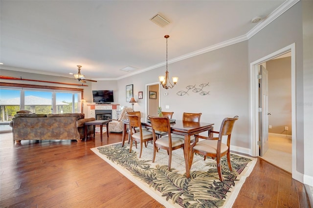 dining area featuring ceiling fan with notable chandelier, hardwood / wood-style flooring, and crown molding