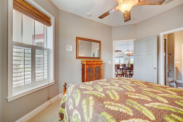 carpeted bedroom featuring ceiling fan with notable chandelier and connected bathroom