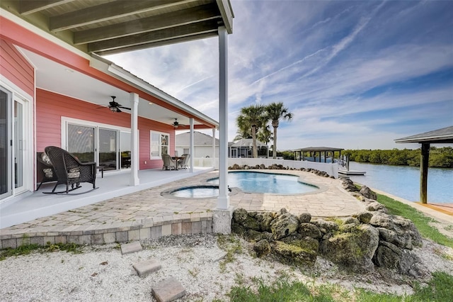 view of swimming pool featuring a patio, a water view, ceiling fan, and a jacuzzi