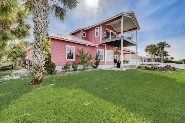 back of house with a balcony, a lawn, and a patio area