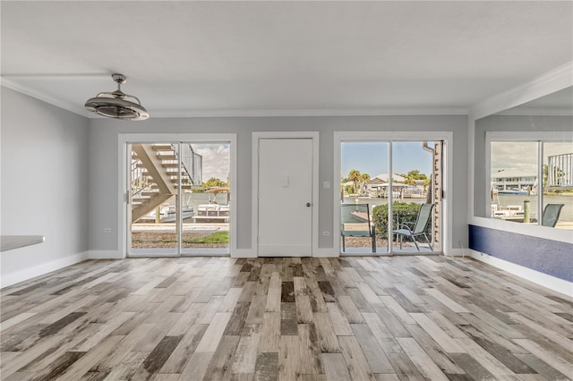 interior space featuring ceiling fan, light wood-type flooring, and ornamental molding