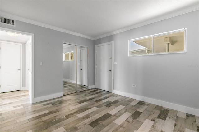 unfurnished bedroom with ornamental molding, wood-type flooring, and a closet