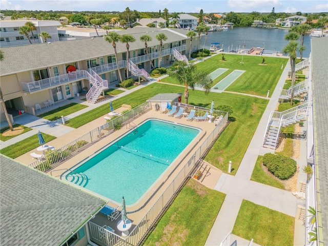 view of pool with a patio, a yard, and a water view