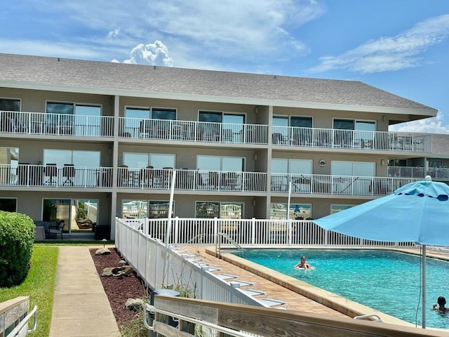 rear view of house featuring a balcony and a community pool