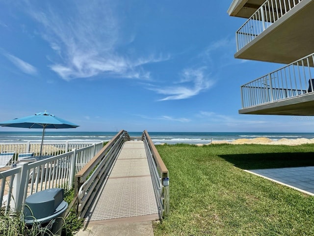 view of property's community featuring a view of the beach, a water view, and a yard