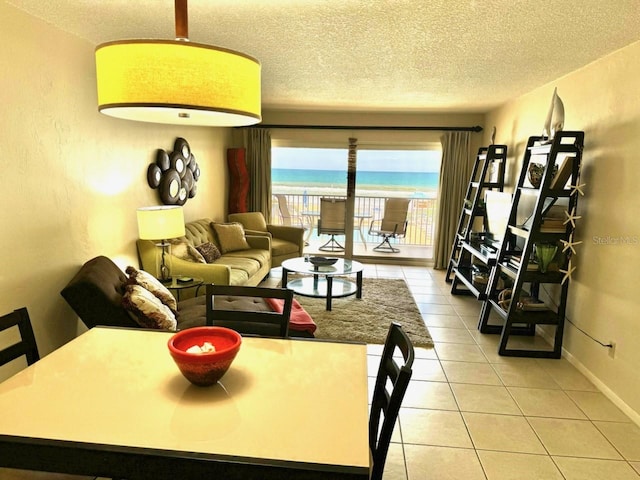 tiled living room featuring a water view and a textured ceiling