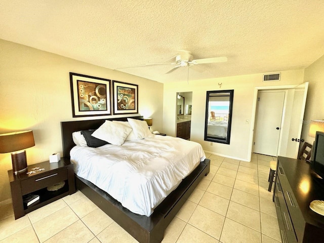 tiled bedroom featuring ceiling fan, a textured ceiling, and connected bathroom