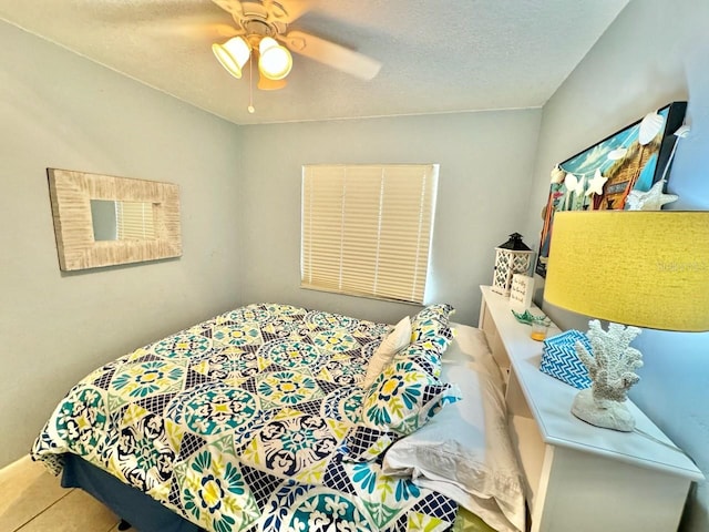 bedroom featuring ceiling fan, a textured ceiling, and tile patterned floors