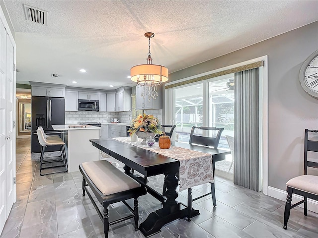 dining room with a notable chandelier, sink, and a textured ceiling