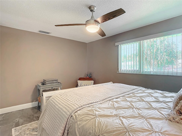 bedroom with ceiling fan and a textured ceiling