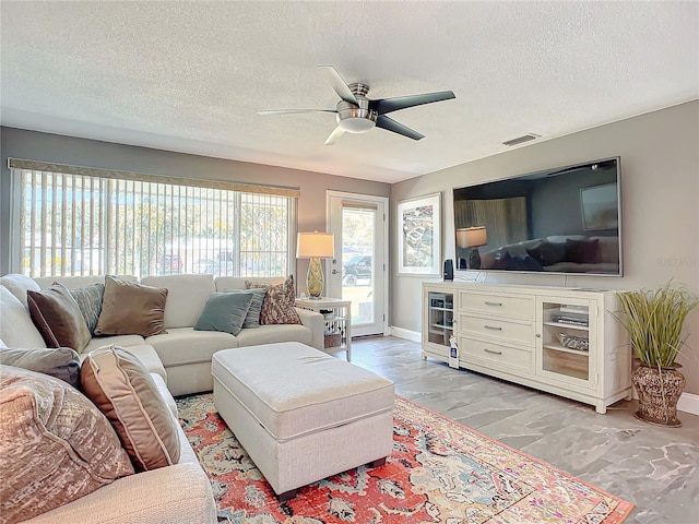 living room featuring ceiling fan and a textured ceiling