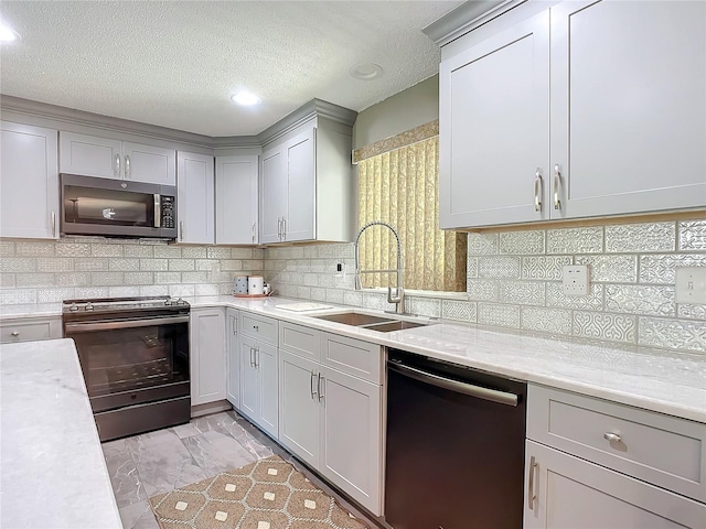 kitchen featuring light stone countertops, sink, a textured ceiling, gray cabinets, and appliances with stainless steel finishes