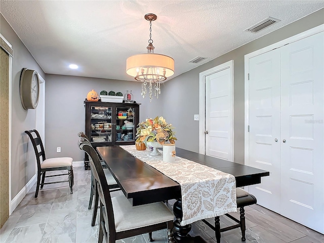 dining room featuring a textured ceiling and a chandelier