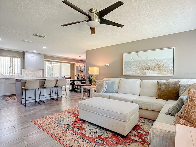 living room featuring ceiling fan, sink, and a textured ceiling