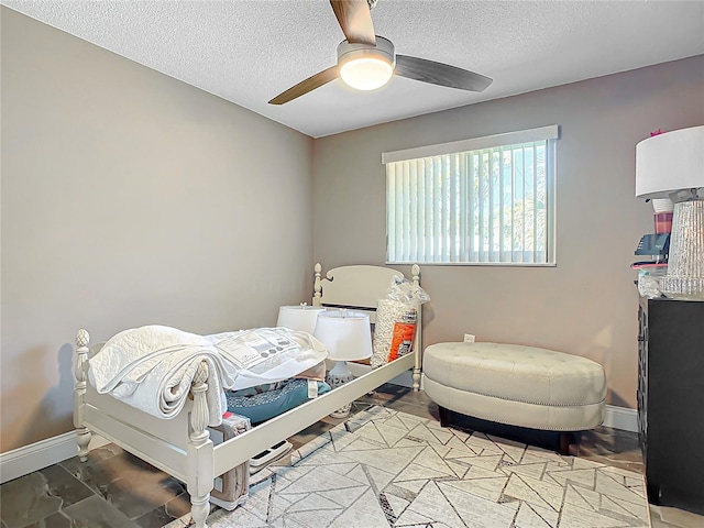 bedroom with ceiling fan and a textured ceiling