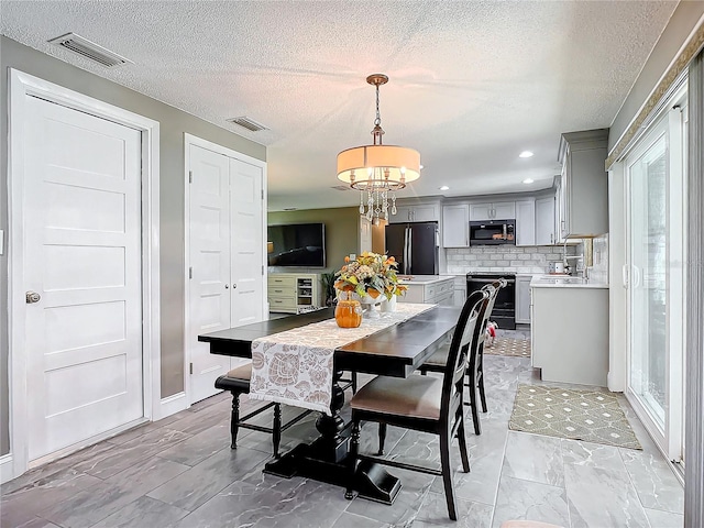 dining area featuring a healthy amount of sunlight, a textured ceiling, and a notable chandelier