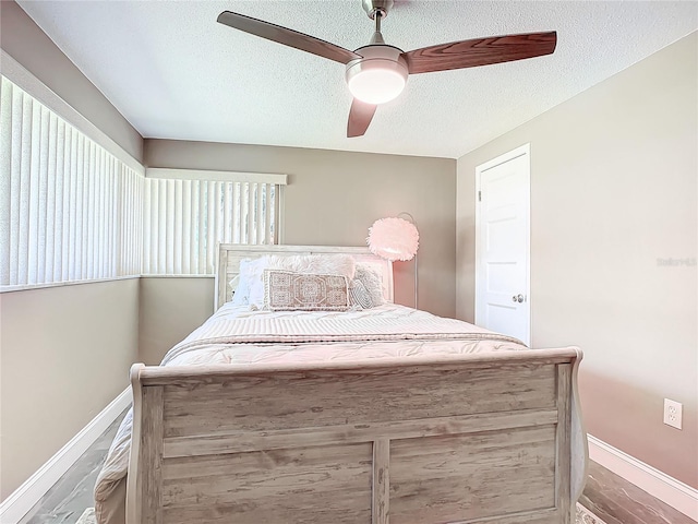 bedroom with ceiling fan, wood-type flooring, and a textured ceiling