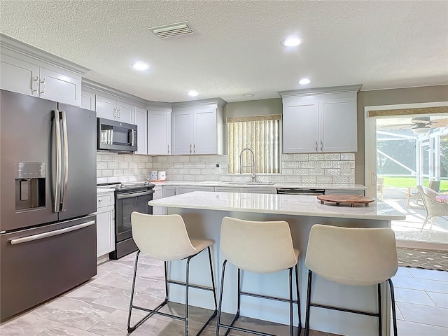 kitchen with backsplash, stainless steel appliances, a kitchen island, and sink