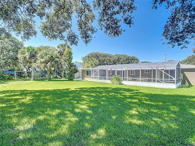 rear view of property with glass enclosure and a yard