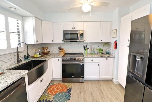 kitchen featuring white cabinets, backsplash, appliances with stainless steel finishes, and sink