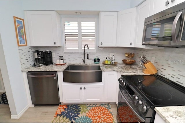 kitchen featuring light stone counters, sink, white cabinets, decorative backsplash, and appliances with stainless steel finishes