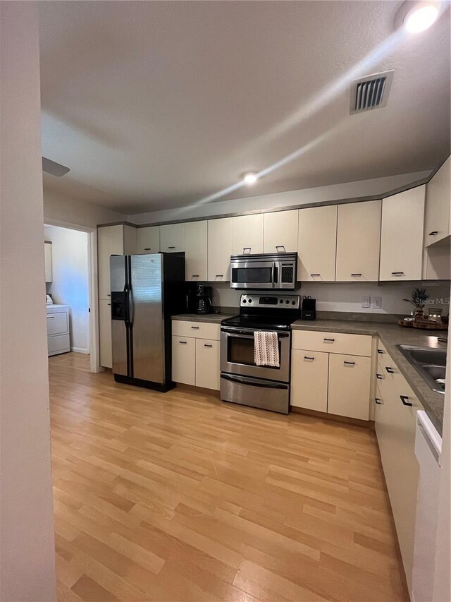 kitchen featuring washer / clothes dryer, sink, stainless steel appliances, and light hardwood / wood-style flooring