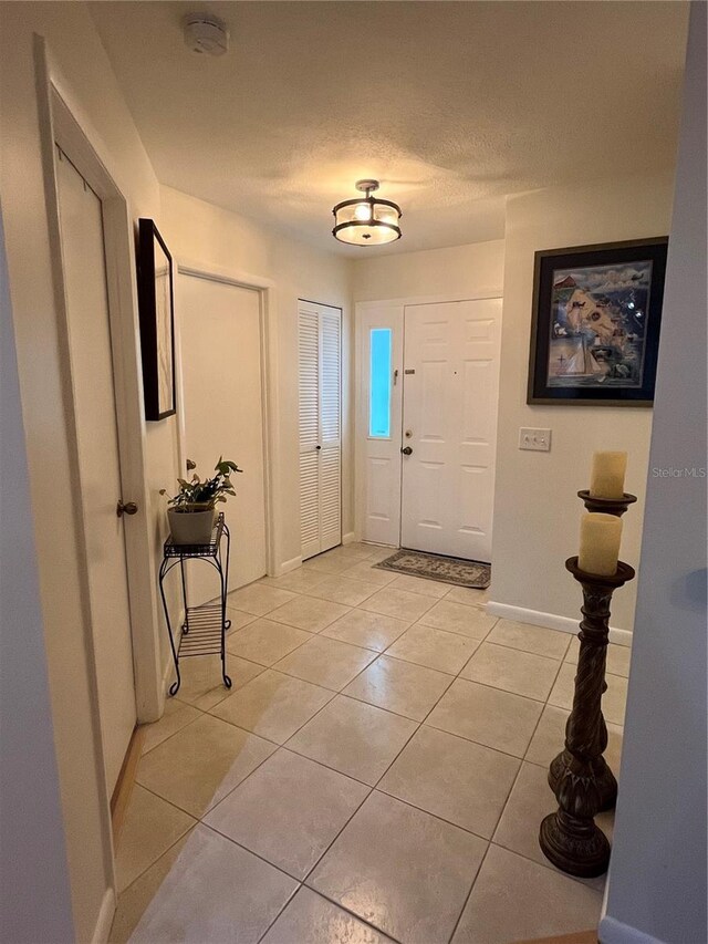 foyer featuring light tile patterned flooring and a textured ceiling