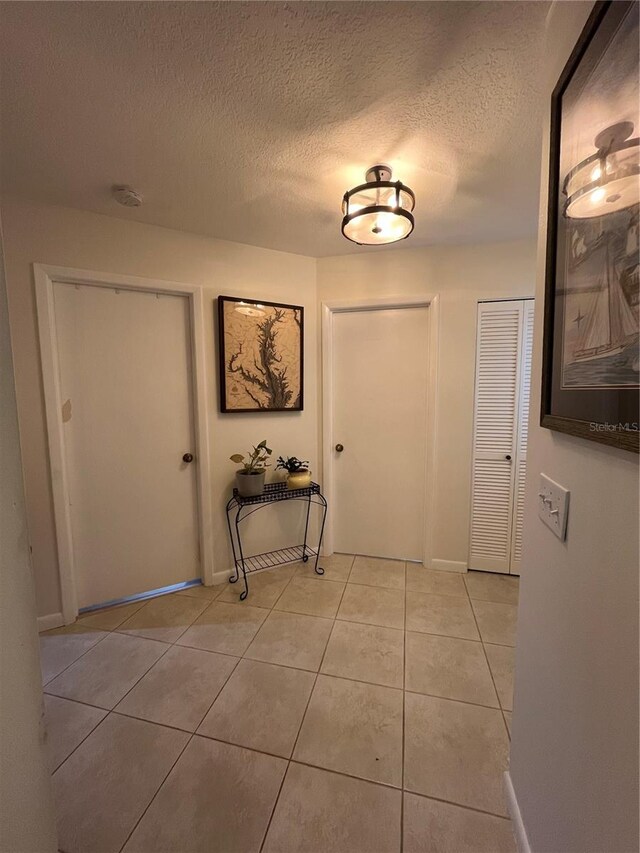 hallway featuring a textured ceiling and light tile patterned floors