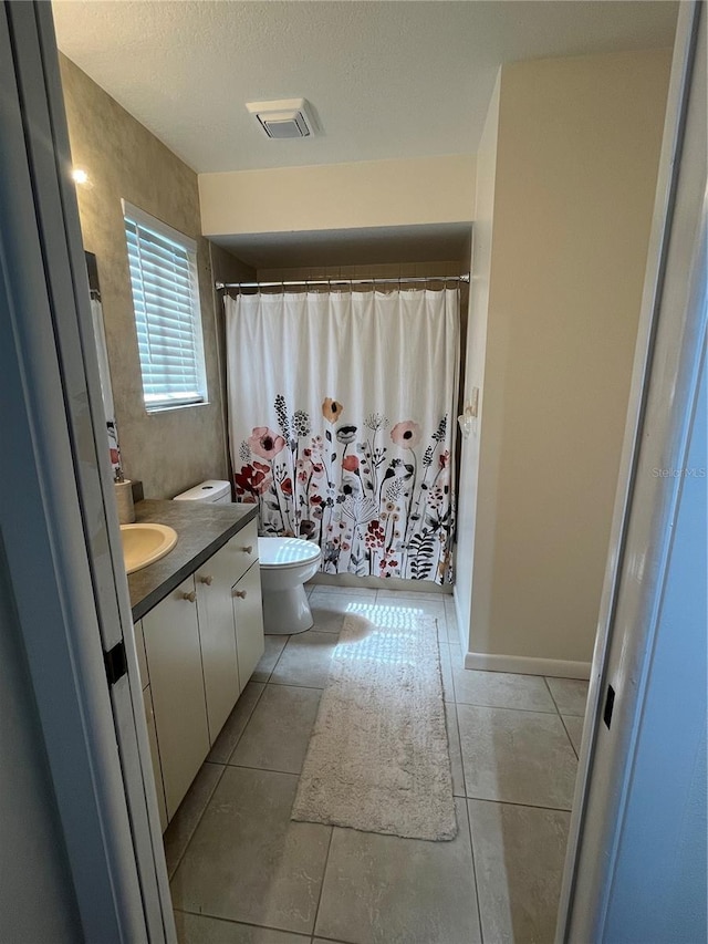 bathroom with a textured ceiling, tile patterned floors, vanity, and toilet