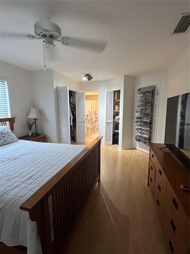 bedroom featuring ceiling fan, a textured ceiling, a closet, light wood-type flooring, and ensuite bath