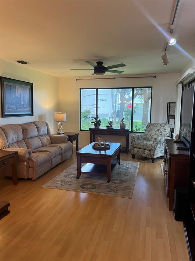 living room with light hardwood / wood-style floors, track lighting, and ceiling fan