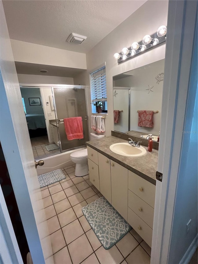 bathroom featuring vanity, toilet, a textured ceiling, and tile patterned floors